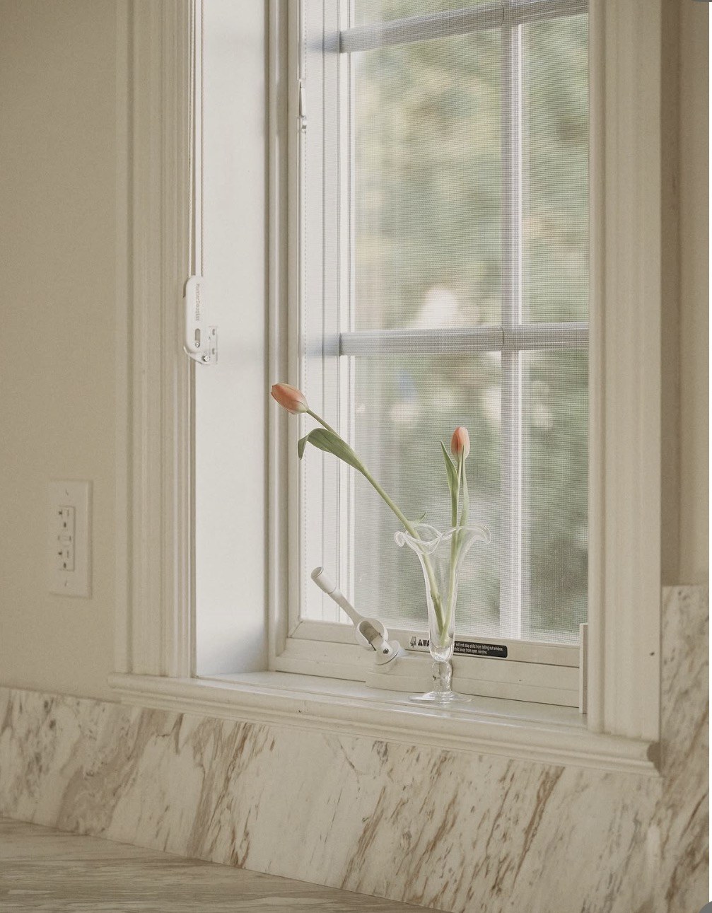 Veined stone backsplash and window detail with flowers