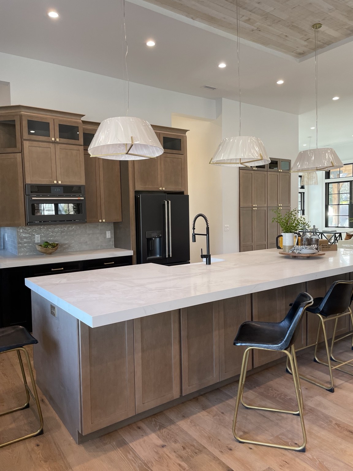 Warm wood cabinetry with a white countertop island and black bar stools