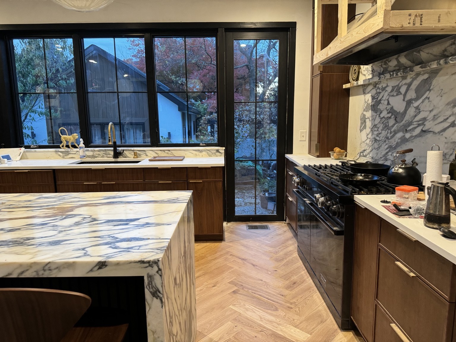 Wood kitchen cabinetry with a veined stone island and backsplash